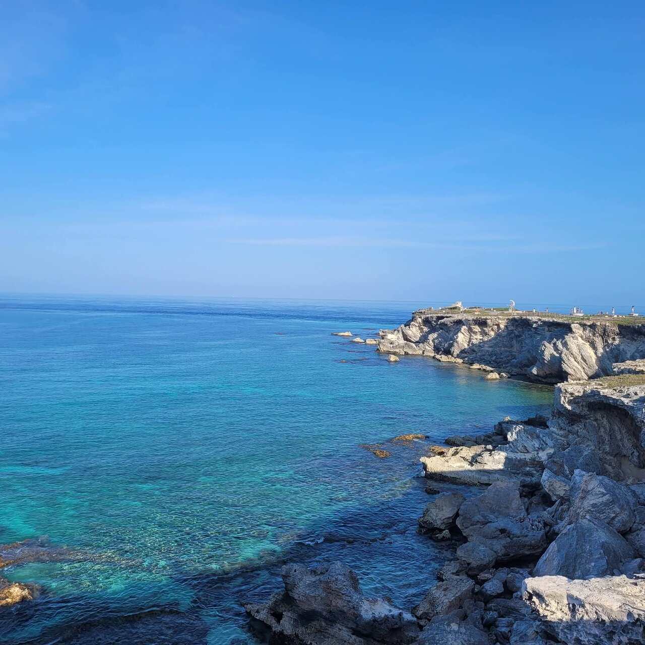 A rocky point above clear turquoise water, the sea stretching away